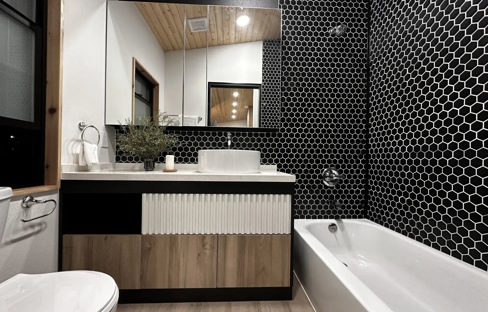 Clever Tiny Homes interior bathroom picture showing vanity, medicine cabinet and bathtub with tile